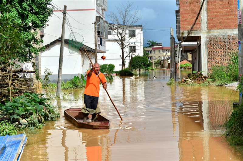 7月3日，桂林市雁山區雁山鎮的一名村民撐船駛出被洪水淹沒的村莊。