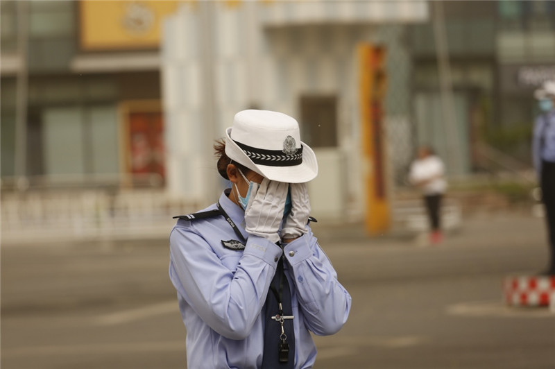 5月5日，在河北省廊坊市街頭，一名交警掩面躲避風沙。