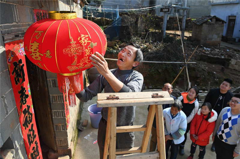 江西鄱陽縣古縣渡鎮張家坽村村民張雪運（左一）在家門口掛燈籠，喜迎新春佳節（1月24日攝）。