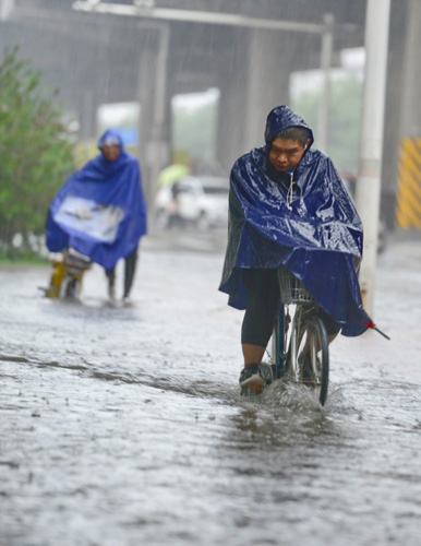 7月20日，一位石家莊市民在槐安路冒雨涉水騎行。