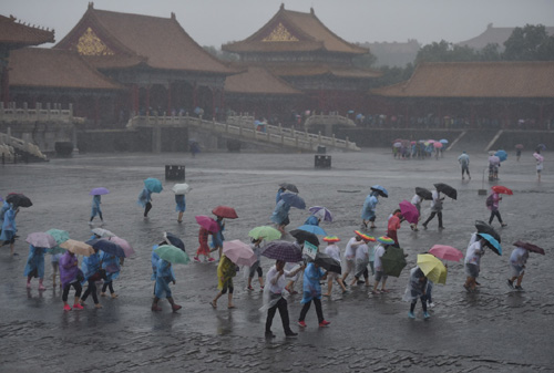 7月20日，游客冒雨在北京故宮游覽。