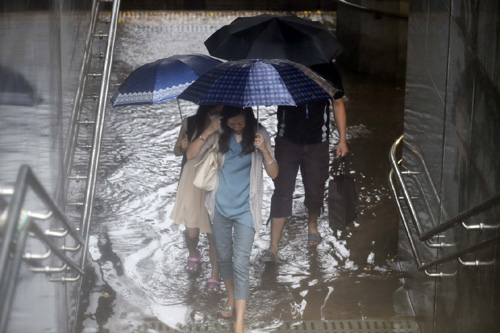 7月20日，行人在北京羊坊店路一個地下通道涉水通過。