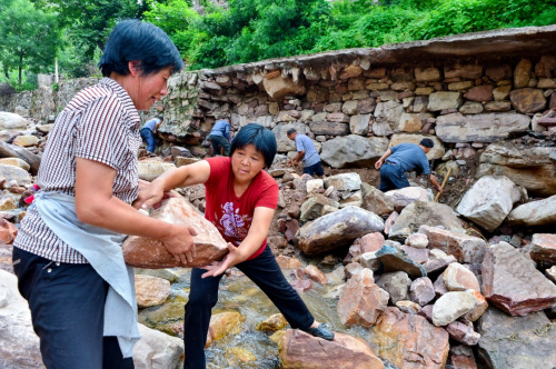8月6日，河北省沙河市柴關鄉陰河溝村村民在壘筑被洪水沖毀的道路。新華社記者 牟宇 攝