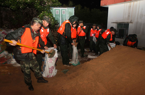 8月18日，武警海南省總隊官兵在裝填沙袋。日前，受南海熱帶低壓影響，海南多地出現強降雨，多個鄉鎮降雨量超過200毫米。18日凌晨，位于海南東環高鐵美蘭段沿線的?？谑忻捞m區大頂村低洼地積水嚴重，部分地段出現積水倒灌現象，武警海南省總隊組織200余名官兵在雨夜趕赴一線搶險救災。目前，險情已基本得到控制。新華社發（楊瑞明 攝）
