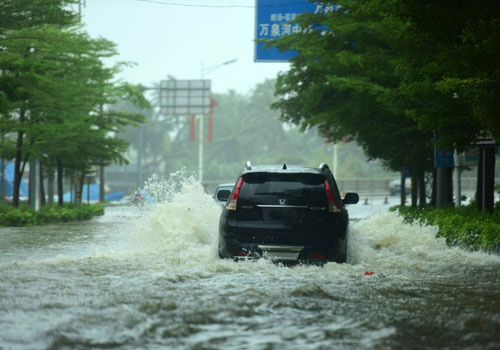 10月18日，一輛汽車在海南瓊海街頭的積水中行駛。