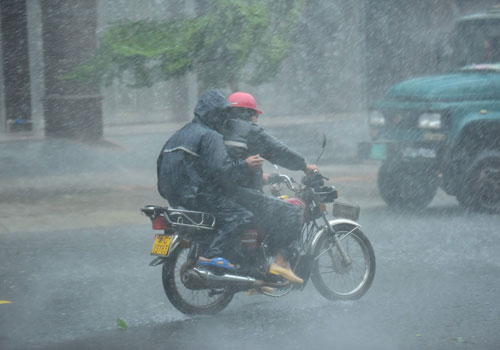 10月18日，在海南瓊海街頭，人們在暴雨中出行。