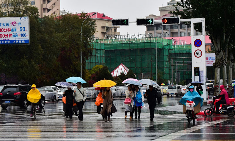 10月27日，在呼和浩特街頭，行人在雨中通過斑馬線。