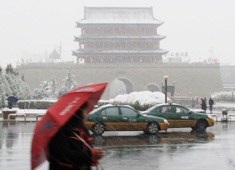 10月27日，車輛和行人冒雪在武威街頭行進。