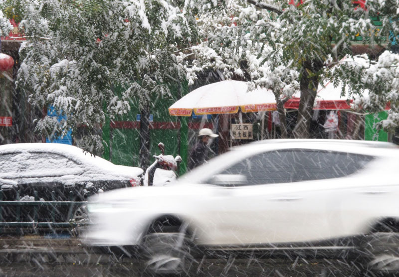 10月27日，車輛和行人冒雪在武威街頭行進。
