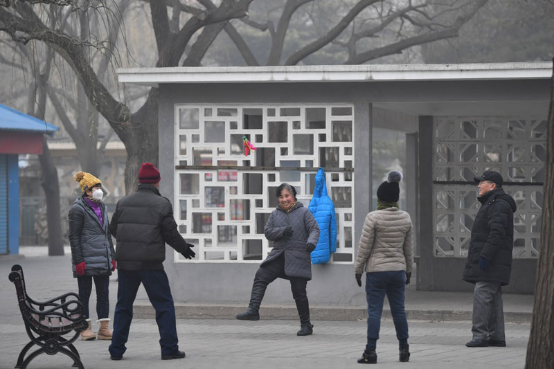 12月21日，幾名市民在霧霾籠罩的陶然亭公園內踢毽子。
